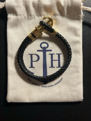 Paul Hewirt armband - Ett armband i guld och svart från Paul Hewitt. Det är i nyskick och jag säljer för att det inte passar.