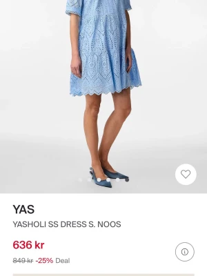 Ljusblå kort klänning från YAS - Supersöt ljusblå klänning från YAS med kort ärm och broderade spetsdetaljer. Klänningen har ett genomgående hålmönster, volangkant nertill och en luftig passform. Perfekt för varma dagar och har en feminin vibe med sin scallopade nederkant.