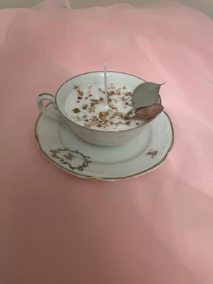 Doftljus i en vaniljdoft i en vit tekopp med blommor på nr 4 - Det här ljuset är gjort av återanvändbara material. Tekoppen är köpt secondhand och stearinet är från kyrkor som tänkte slänga det. Det här ljuset har en svag doft utav vanilj, så känsliga även kan använda det. Det här ljuset har även torkade blommor på som dekoration. Det finns fler av denna design på hemsidan om man vill köpa sets. 