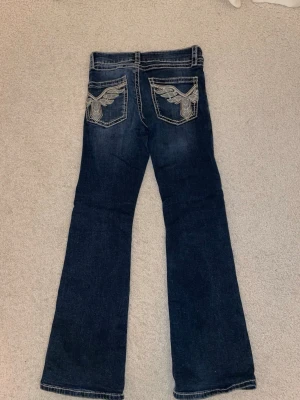 Blå bootcut jeans från Gina Tricot - Mörkblå bootcut jeans från Gina Tricot med broderade glitterdetaljer på bakfickorna.🩷