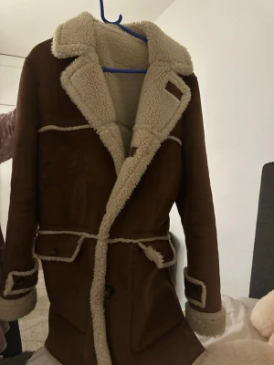 Brun jacka/kappa från Zara Man - Säljer en brun jacka från Zara Man med mjukt, ljust foder och bred krage. Mocka med ull 