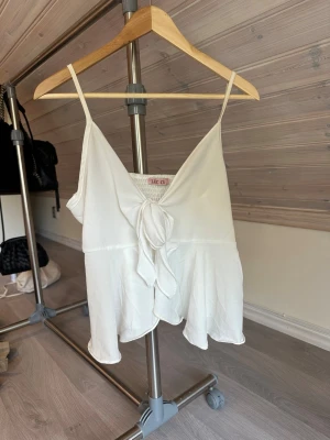 Topp  - Vit topp med knyte vid bysten som går att reglera och även banden är reglerbara, inga defekter. Storlek L men liten i storleken, sitter som en s