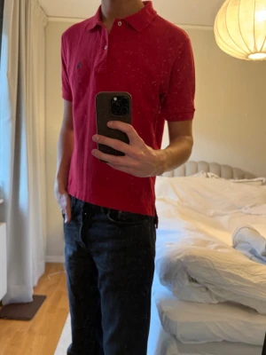 Röd pikétröja från polo Ralph Lauren - Säljer en klassisk röd pikétröja från polo Ralph Lauren med liten broderad logga på bröstet. Tröjan har krage, två knappar vid halsen och korta ärmar. Perfekt till jeans eller shorts för en clean look. Den är storlek M men skulle säga att det är en S