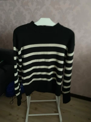 Svartvit randig stickad tröja Gina Tricot - Säljer en svart stickad tröja från Gina Tricot i storlek S. Tröjan har vita horisontella ränder, rund halsringning och långa ärmar. Perfekt för dig som gillar klassisk stil med en twist. Superenkel att matcha till jeans eller kjol.