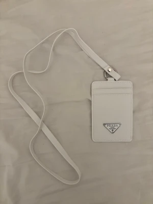 Plånbok med axelrem - Jag säljer en helt oanvänd vit plånbok med axelrem.