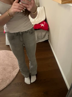 Grå bootcut jeans från denim day - Säljer ett par gråa jeans med bootcut-modell. Jeansen har klassiska fem fickor och är tillverkade i ett stretchigt jeanstyg. Snygg passform som sitter tajt upptill och släpper ut vid benen.
