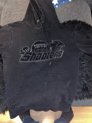 Svarta mjukisbyxor Trapstar London - Svarta mjukisbyxor från Trapstar London med broderad logga och pantermotiv framtill. Byxorna har resår och snörning i midjan samt muddar vid bensluten. Perfekta för en chill och avslappnad stil.