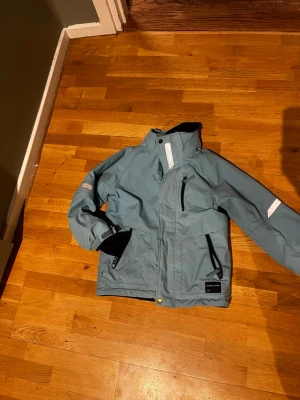 Blå vinterjacka Polarn O. Pyret 134 - Blå vinterjacka från Polarn O. Pyret med reflexdetaljer på ärmarna och bröstet. Jackan har dragkedjor på fickorna, halvhög krage och mjukt fleecefoder på insidan. Finns en liten reva vid en framfickan men påverkar inget direkt, men priset därav. Kommer från ett djur- och rökfritt hem. 