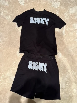 Risky shorts tshirt sett - Bilderna visar ett svart t-shirt och shorts-set med texten 'RISKY' i vitt framtill.
