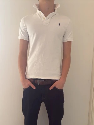 Vit pikétröja Polo Ralph Lauren (Bundle) - Vit pikétröja från Polo Ralph Lauren i slim modell. Modellen på bilden är c.a 180cm. Pikén är i storlek 14-16 år men passar även dig som har XS. Bundle är möjligt med den mörkblå pikén. Tveka inte på att höra av er vid minsta fundering!