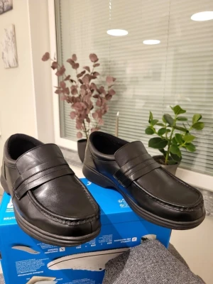 Svarta loafers från Dr. Scholl's 43 wide 9W - Stilrena svarta loafers från Dr. Scholl's i skinn med klassisk design och platt sula. Skorna har rund tå och diskreta sömmar framtill, perfekt för dig som vill ha en enkel och bekväm sko med snygg look. Samfraktar gärna!