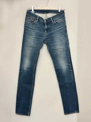 Acne Studios Blå Konst jeans blå - Snygga blå jeans från Acne Studios Blå Konst, modell North, i klassisk tvättad denim. De har raka ben, fem fickor och normal passform. Materialet är bomull med lite elastan för extra komfort. Perfekta för dig som gillar stilrena och moderna jeans.