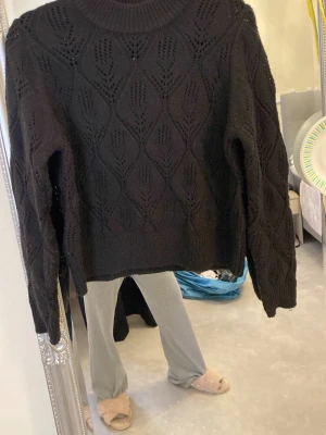 Stickad tröja med mönster - Säljer en svart stickad tröja med snyggt hålmönster i hela plagget. Tröjan har lång ärm, ribbad halsringning och muddar. Den är varm och mysig🥰