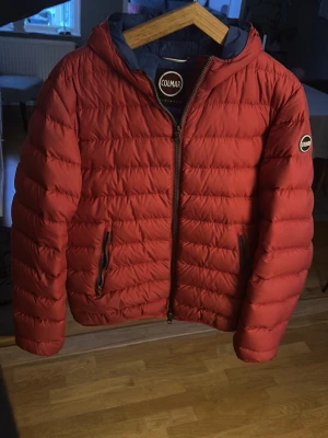 Colmar jacka - Säljer en röd pufferjacka från Colmar. Perfekt för kyliga dagar och riktigt skön att bära. Klassisk quiltad design och hel dragkedja framtill. Litet jack på luvan (se sista bilden) annars felfri👍🏻