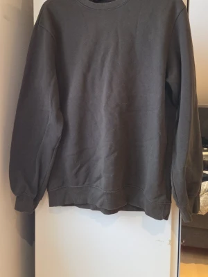 Svart crewneck sweatshirt från H&M - En svart crewneck sweatshirt från H&M i relaxed fit. Tröjan har rund halsringning, långa ärmar och ribbade muddar vid ärmslut och nederkant. Perfekt för en chill och avslappnad stil.