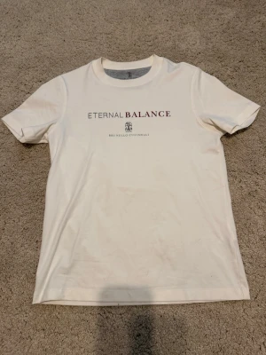 Vit t-shirt från Brunello Cucinelli - Säljer en vit t-shirt från Brunello Cucinelli med trycket ‘ETERNAL BALANCE’ på bröstet och logo under. Andrig använd, sparsamt använd. Nypris cirka 650 euro. Inga kvitton kvar. Välkomnar seriösa prisförslag