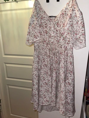 Blommig vit klänning från SHEIN - Supersöt vit klänning från SHEIN med små blommor i rött, grönt och blått. Klänningen har v-ringning, knappar framtill och korta ärmar. Perfekt flowy passform och lätt material som känns luftigt under varma dagar.