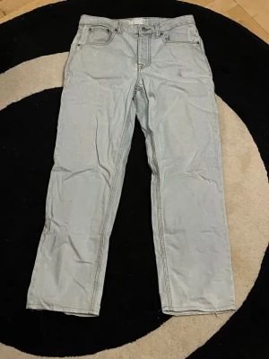 Ljusblå jeans från ASOS Design - Säljer ett par ljusblå jeans från ASOS Design i klassisk rak modell. Jeansen har fem fickor, bälteshällor och knappgylf. Tillverkade i bomull med snygga kontrastsömmar. Perfekta för dig som gillar en enkel och clean look. Storlek W29 L30.