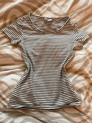 Randig t-shirt från H&M Basic XS - Säljer en vit och svart randig t-shirt från H&M Basic i storlek XS. T-shirten har rund halsringning och korta ärmar. Materialet är mjuk bomull som känns skönt mot huden. Perfekt för dig som gillar enkel och stilren design.