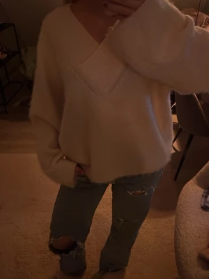 Beige stickad tröja Gina Tricot - Mysig beige stickad tröja från Gina Tricot med djup v-ringning och bred ribbad kant runt halsen. Tröjan har en loose passform och långa ärmar, Superenkel att styla till vad som helst. Helt ny och aldrig använd 💗