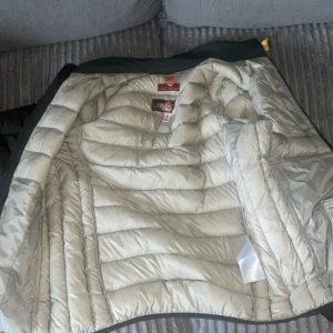 Parajumpers dunjacka mörkgrön M - Säljer en Parajumpers dunjacka i mörkgrönt med klassisk gul detalj vid kragen. Jackan är superlätt, har quiltad design och dragkedja framtill. Perfekt för kalla dagar och riktigt snygg passform. Fodret är ljust och jackan har lång ärm.