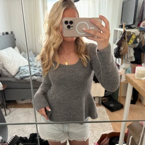 Grå stickad tröja med utsvängd midja - Mysig grå stickad tröja med rund halsringning och lång ärm. Tröjan har en lätt utsvängd passform vid midjan som ger en snygg siluett. Perfekt att matcha med jeans eller kjol för en chill look.