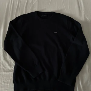 Svart bomullströja från Lexington - Klassisk svart tröja från Lexington i bomull med rund hals och diskret logga på bröstet. Långärmad modell med ribbade muddar vid ärmslut och nederkant. Perfekt för en stilren och enkel look. Köpte den för runt 900kr o säljer för 599kr, passar perfekt på folk runt 160cm-175cm