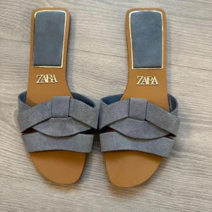 smutsblå mockasandaler från Zara - Snygga sandaler från Zara i smutsblå mocka med flätad design över foten och fyrkantig tå. Platt sula och stilren look som passar perfekt till alla tillfällen!. Storlek 37. Använda 1 gång och passar mer till dem med lite smalare fötter för passformen är väldigt smal 😅🤗