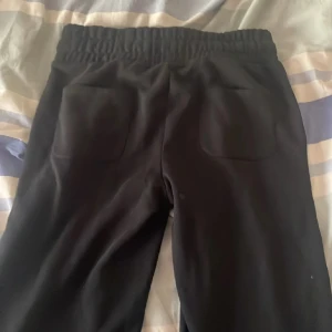 Svarta mjukisbyxor från 157, storlek S - Svarta mjukisbyxor från 157 med elastisk midja och snörning. Byxorna har två fickor fram och två bak, raka ben och är tillverkade i mjukt material som är skönt att ha på sig. Perfekta för chill eller träning.