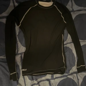 Svarta underställsbyxor från Velli - Svarta underställsbyxor från Velli med kontrasterande vita sömmar. Byxorna är tighta och gjorda i ett mjukt syntetmaterial som är perfekt för träning eller kalla dagar. Snyggt sportig look med diskret logga vid midjan.