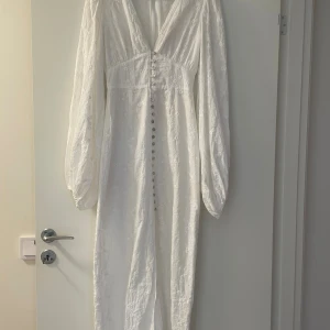 Vit långklänning från Adoore - Superfin vit långklänning från Adoore med broderade blommor, v-ringning och knappar framtill. Bara använd 2 gånger. Nypris 1695 kr