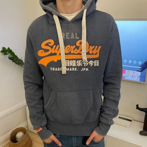Grå Superdry hoodie med tryck - Snygg grå superdry hoodie. Modellen är 183. Nypris 1500! Hör av dig vid minsta fundering🤗