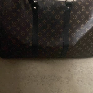 Louis Vuitton resväska monogram - Stor och rymlig resväska från Louis Vuitton med klassiskt monogrammönster i brunt och beige. Väskan har svarta detaljer, axelrem med logga och insida i glansigt rött tyg med LV-mönster. Perfekt för dig som vill resa med stil. Kan tänka mig gå ner i pris vid snabb affär 
