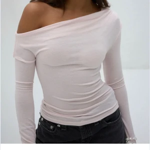Ljusrosa offshoulder topp - Säljer en ljusrosa offshoulder topp med lång ärm och slim passform. Toppen är tillverkad i mjukt, stretchigt material som sitter skönt mot kroppen. Perfekt för dig som gillar en clean och feminin look.