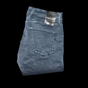 Replay Hyperflex jeans blå 34/32 - Säljer ett par Replay Hyperflex jeans i mörkblå tvätt. Modellen har smal passform med klassiska fem fickor, silverfärgad patch bak och stretchigt material för extra komfort. Perfekta för dig som gillar stilrena och bekväma jeans. OBS har en fläck fram på högerben. Längd 98cm, midja 42cm. S2