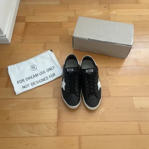 Svarta Golden Goose sneakers med stjärna - Säljer ett par riktigt snygga Golden Goose sneakers i storlek 45 men passar lite mindre-De är i bra skick-Box och dustbag ingår-Självklart äkta-Äktenhetsbevis finns-Det är bara att hör av sig vid eventuella frågor-Kan gå ner i pris vid snabb affär!✌️👑