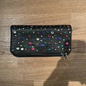 Svart axelväska (modell rock) från Zadig & Voltaire - Cool svart axelväska i skinn från Zadig & Voltaire med färgglada pärlor och nitar på framsidan. Väskan har silverfärgade dragkedjor och en kedja med läderdetaljer som axelrem. Perfekt storlek för det viktigaste och ger en edgy vibe till din outfit. Köpt nypris för 2800 men säljer ursprungligen från 1500! Har ni några frågor är det bara att skriva :) 
