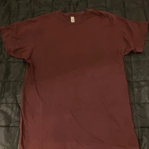 Vinröd t-shirt från American Apparel - Enkel och stilren vinröd t-shirt från American Apparel. Modellen är klassisk med rund hals och korta ärmar. Tillverkad i mjuk bomull som känns skön mot huden. Perfekt för dig som gillar basic plagg med snygg färg.