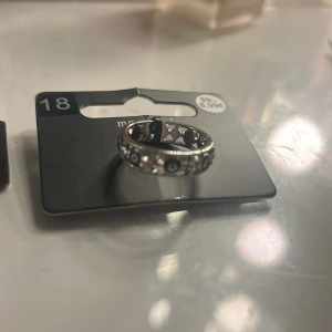 Silverfärgad ring med blå evil eye - Cool silverfärgad ring från Montini med blå och vita evil eye-detaljer runt hela ringen. Ringen har en snygg glittrig finish och är perfekt för dig som vill sticka ut med en unik accessoar. Båda för 79
