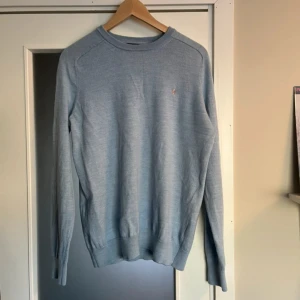 Ljusblå merinoullströja från Morris - Säljer en stilren ljusblå tröja från Morris i 100% merinoull. Tröjan har rund halsringning, diskret broderad logga på bröstet och långa ärmar. Perfekt för lager-på-lager och passar till både jeans och chinos. Storlek L passar M