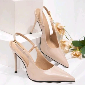 Beiga pumps med spetsig tå och klack - Snygga pumps i beige lack med spetsig tå och hög klack. Skorna har öppen häl med smal rem och elegant design som ger en stilren look. Perfekta för dig som vill sticka ut med klassiska och trendiga skor.