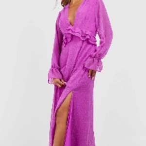 Lila långklänning med volangdetalj - Långklänning i lila med transparenta, långärmade ärmar. Klänningen har v-ringning och volangdetalj i midjan. Aldrig använd. 