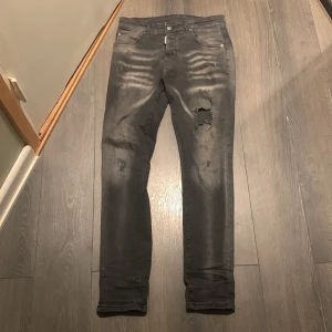 Svarta skinny jeans från Dsquared2 - Säljer ett par svarta jeans från Dsquared2 med slitningar och hål på ena benet. Jeansen har en snygg tvättad look och klassisk femficksdesign. Mycket bra skick endast använda några få gånger. 