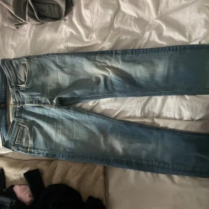 Ljusblå Lee jeans straight fit - Säljer ett par ljusblå jeans från Lee med klassisk femficksdesign och snygga slitningar. Jeansen har raka ben och normal passform, perfekt för en avslappnad stil. Materialet är mjukt denim och de har Lee-logga på bakfickan.
