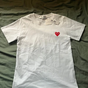Comme des garcons T-shirt - En helt ny comme des garcons T-shirt, Tröjan är aldrig använd och har inga skavanker. Det ikoniska hjärtmotivet på bröstet ger dig en fantastisk look. Fler bilder eller information ges ut vid intresse!😄