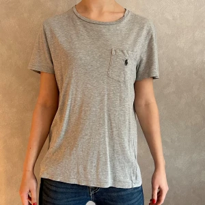 T-Shirt Ralph Lauren - En grå T-Shirt från Polo Ralph Lauren🏇Storlek 170. Mycket fint skick!😄 Skriv vid frågor/ funderingar/ mått! PRISET ÄR ALLTID DISKUTERBART!🥰