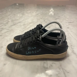 Svarta Saint Laurent sneakers i skinn - Svarta sneakers från saint Laurent. Storlek 37, passar även storlek 38. De är väl använda och lite slitna men generellt  i fint skick. 