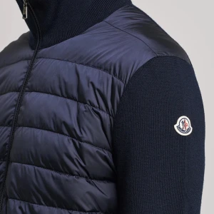 Moncler Cardigan mörkblå  - Säljer en mörkblå cardigan från Moncler med quiltad front i glansigt material och stickade ärmar. Jackan har hög krage, dragkedja framtill och två fickor med dragkedja. Klassisk Moncler-logga på ärmen och stilren design. Använt ett fåtal gånger har kvittot kvar med. Köpt på NK för 10 000kr