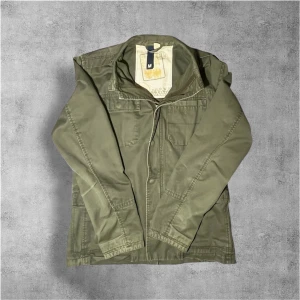 Overshirt/field jacket - Tvärrrrfet Overshirt/fieldjacket i stl M men passar också L (Jag har L). Jackan har raka linjer, långa ärmar och stängs med dragkedja och knappar. Svin snygg jacka men använder den inte längre så den säljs. Hör av dig vid fler frågor!