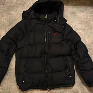 Svart pufferjacka från Polo Ralph Lauren - Säljer en svart pufferjacka från Polo Ralph Lauren som är jätte populär. Använts en vinter men är i nytt skick. ( kan inte frakta förrän på tisdag pga skada)